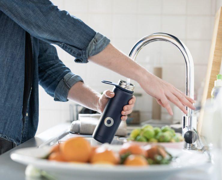 person in blue denim jacket holding stainless steel bottle