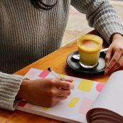 person holding pen with coffee on table