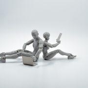 two grey plastic action figures sitting on floor back to back