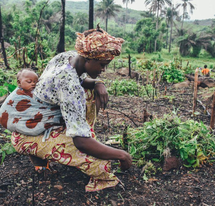 women carrying baby in her back close-up photography