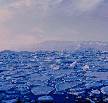 man and woman standing cracked sea ice under gray sky