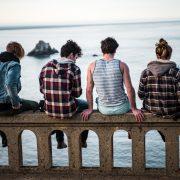 four person sitting on bench in front of body of water