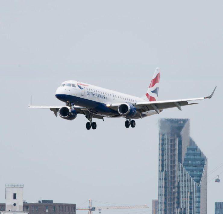 white, red, and blue airplane above buildings