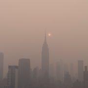 a foggy city skyline with the sun in the distance