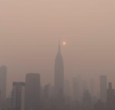 a foggy city skyline with the sun in the distance