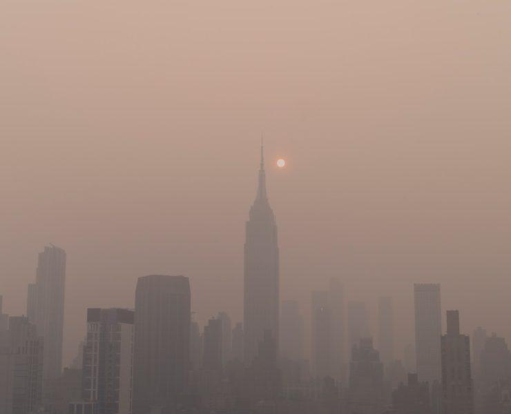 a foggy city skyline with the sun in the distance