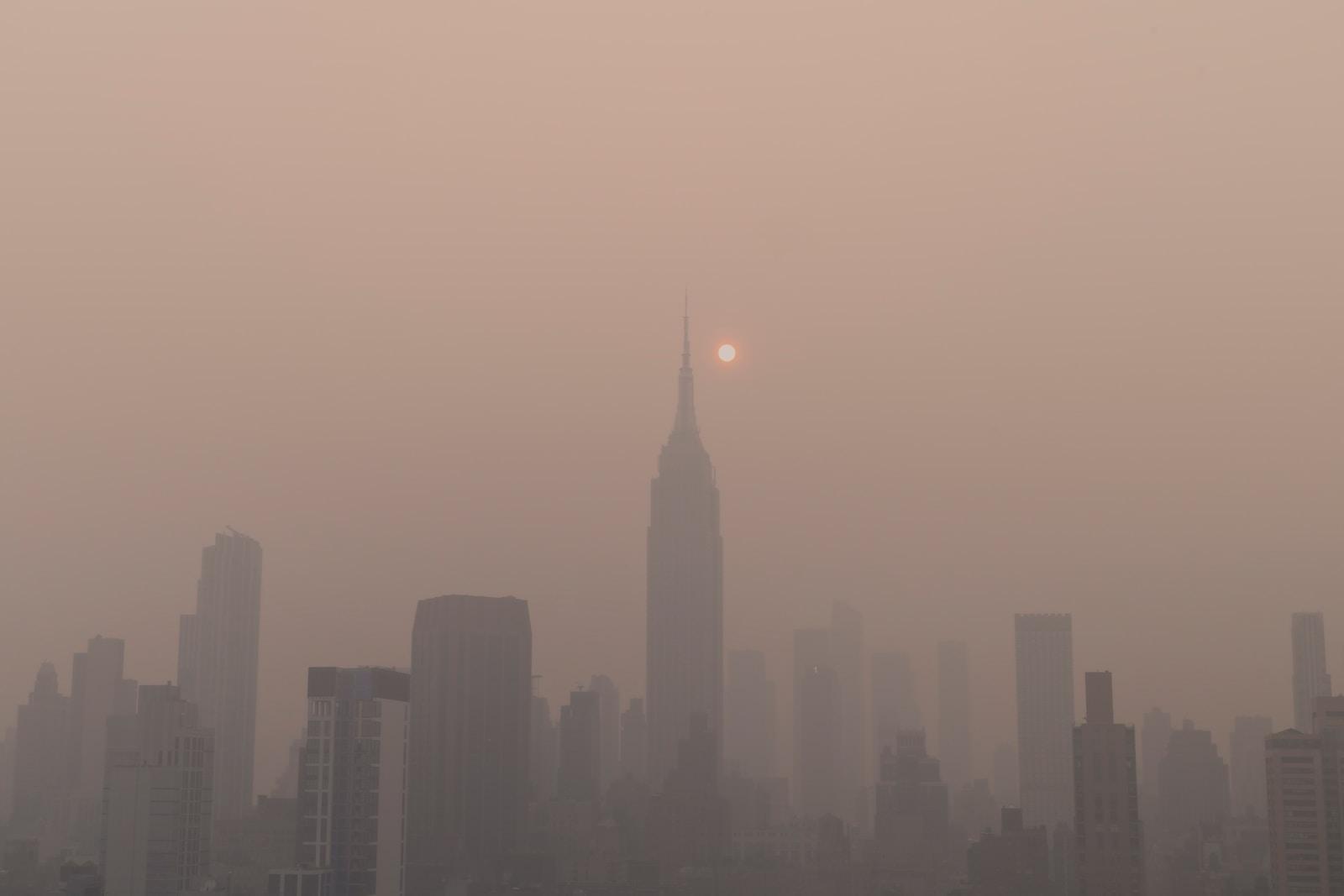 a foggy city skyline with the sun in the distance