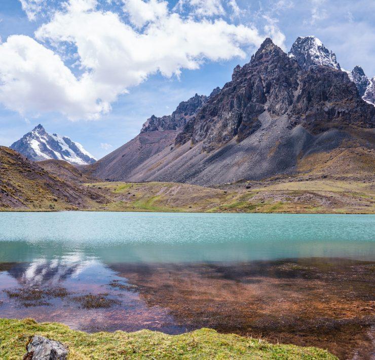 a lake surrounded by mountains under a blue sky