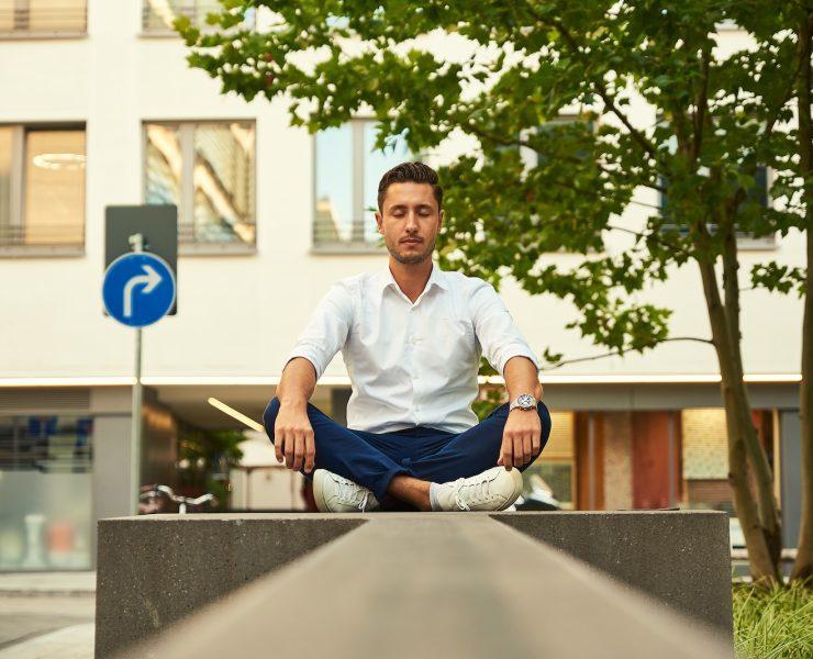 man in white dress shirt sitting on gray concrete bench during daytime