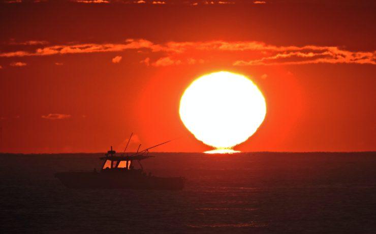 silhouette of person riding on boat during sunset