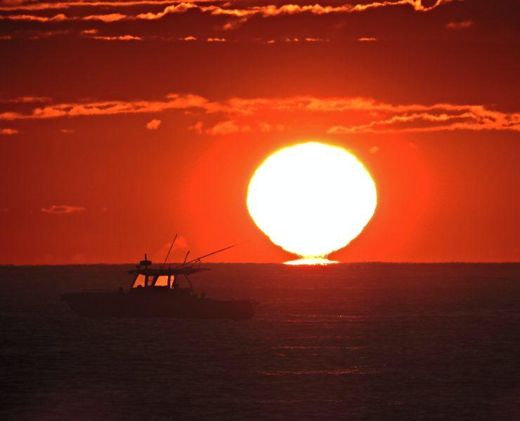silhouette of person riding on boat during sunset