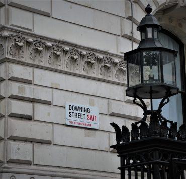 photo of black metal framed glass street post near gray concrete building during daytime