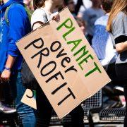 woman holding Planet over Profit placard