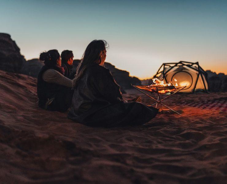 a group of people sitting on top of a sandy beach