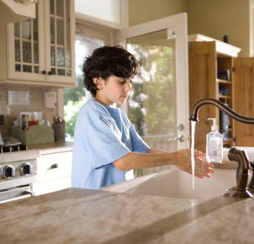 boy in blue polo shirt standing in front of sink