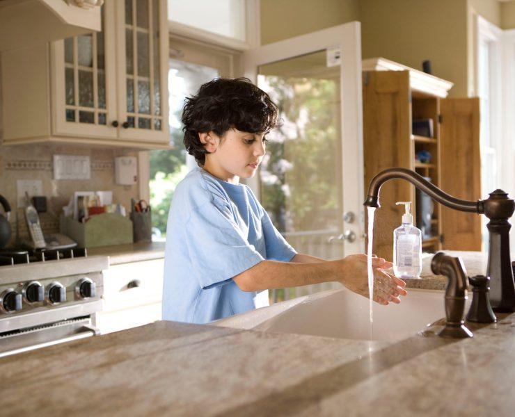 boy in blue polo shirt standing in front of sink