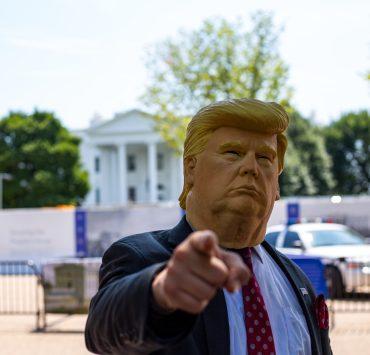 man wearing Donald Trump mask standing in front of White House