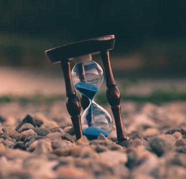 selective focus photo of brown and blue hourglass on stones