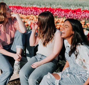 three women sitting wooden bench by the tulip flower field