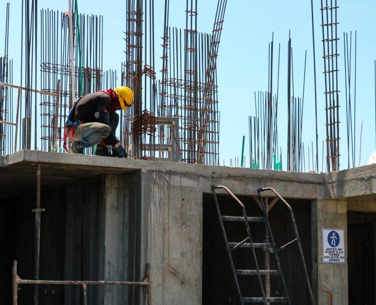 man kneeling on unfinished building during daytime
