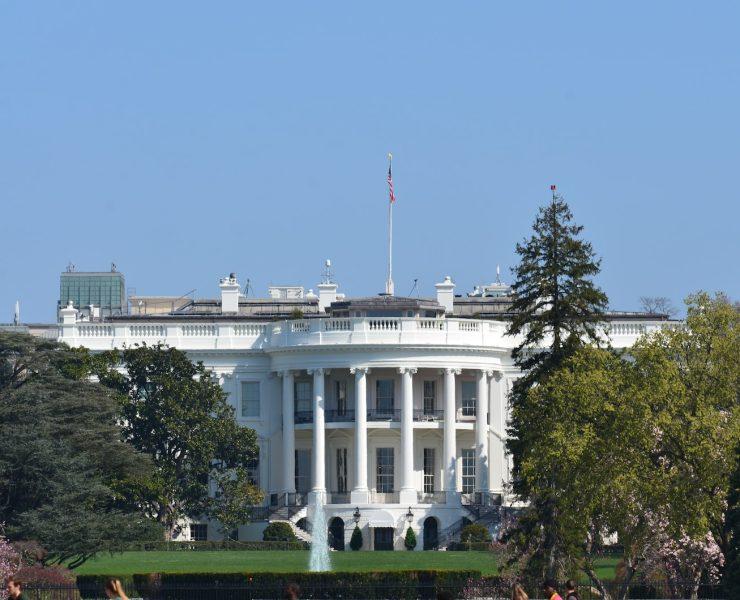 white concrete building near green trees under blue sky during daytime
