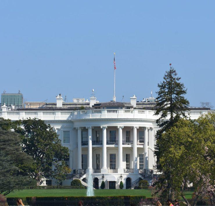 white concrete building near green trees under blue sky during daytime