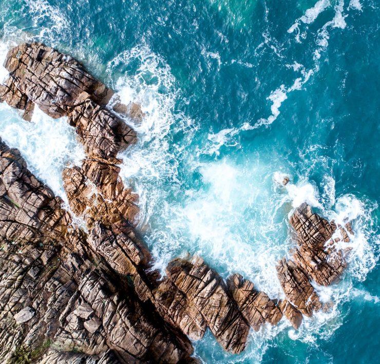 rock mountain next to ocean water