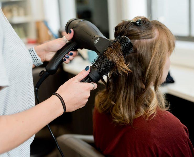 woman in red long sleeve shirt holding hair blower