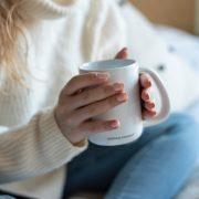 a woman sitting on a bed holding a coffee mug