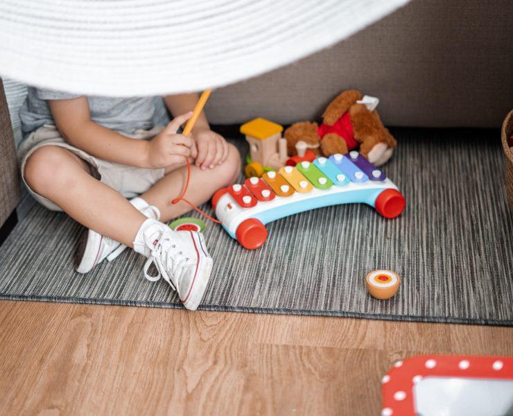 child sitting on floor and playing with xylophone toy