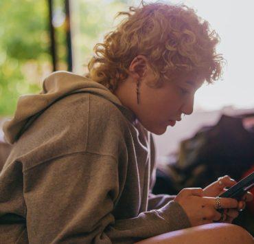 Portrait of a nonbinary autistic person using their mobile phone indoors