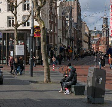 a group of people walking down a street next to tall buildings