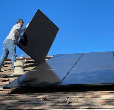man in white dress shirt and blue denim jeans sitting on white and black solar panel