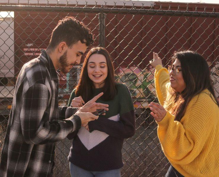 man and two women standing near linked-chain fence