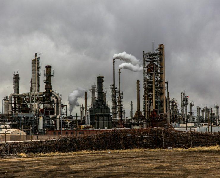 factories with smoke under cloudy sky