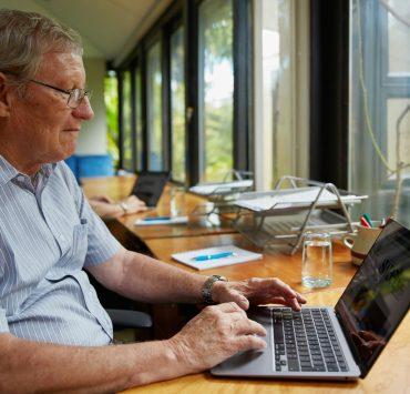 a man sitting at a table using a laptop computer