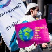 man in white jacket holding purple and white banner