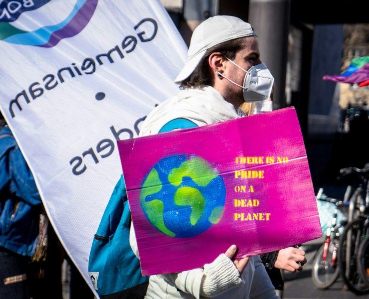 man in white jacket holding purple and white banner