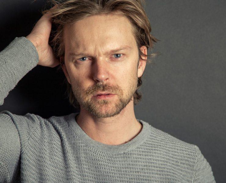 a man with a beard and blue eyes posing for a picture
