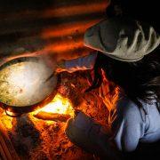 person in gray long sleeve shirt and black hat holding a stainless steel cooking pot