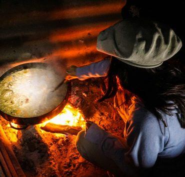 person in gray long sleeve shirt and black hat holding a stainless steel cooking pot