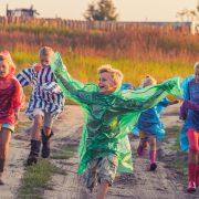 boy in green jacket and red shirt running on road during daytime