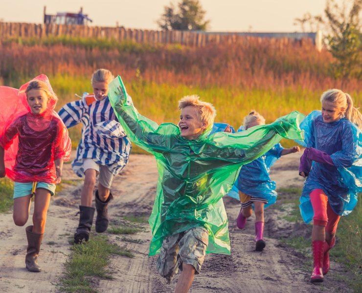 boy in green jacket and red shirt running on road during daytime