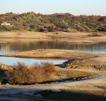 a body of water surrounded by a lush green hillside