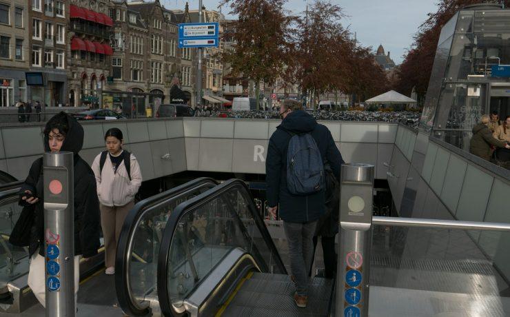 a group of people riding an escalator down a street